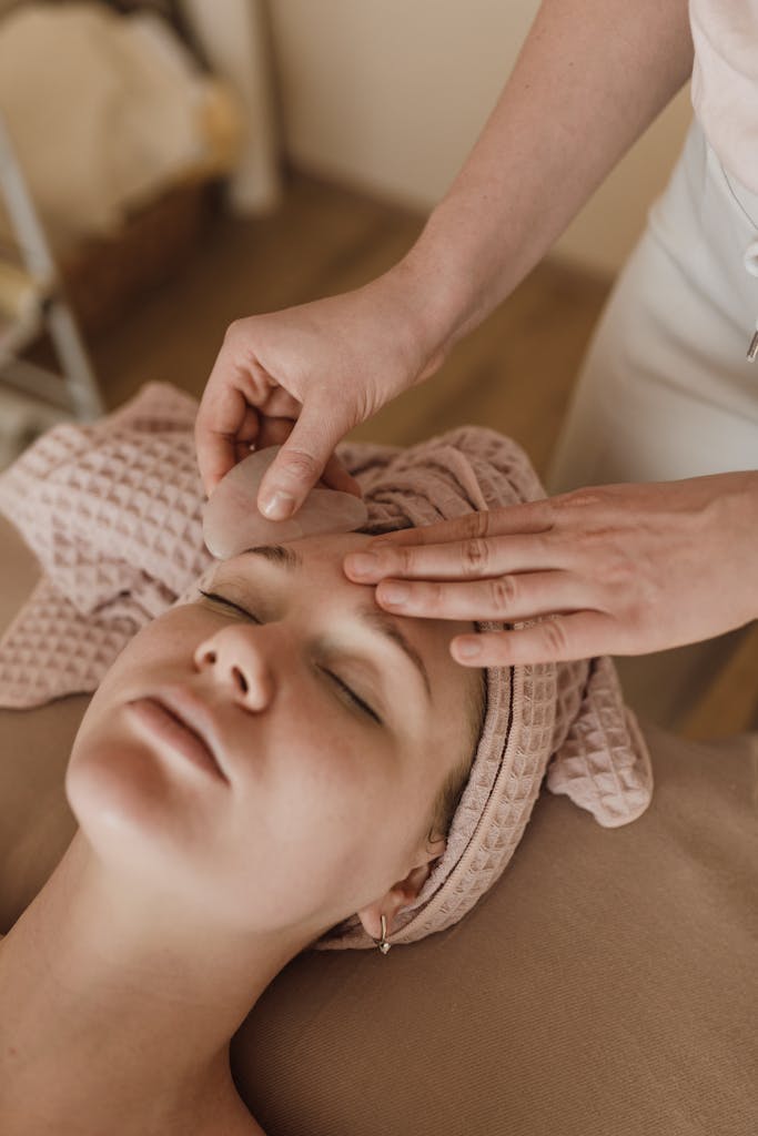 Woman enjoying a soothing facial massage with gua sha tool, promoting relaxation and skin care.